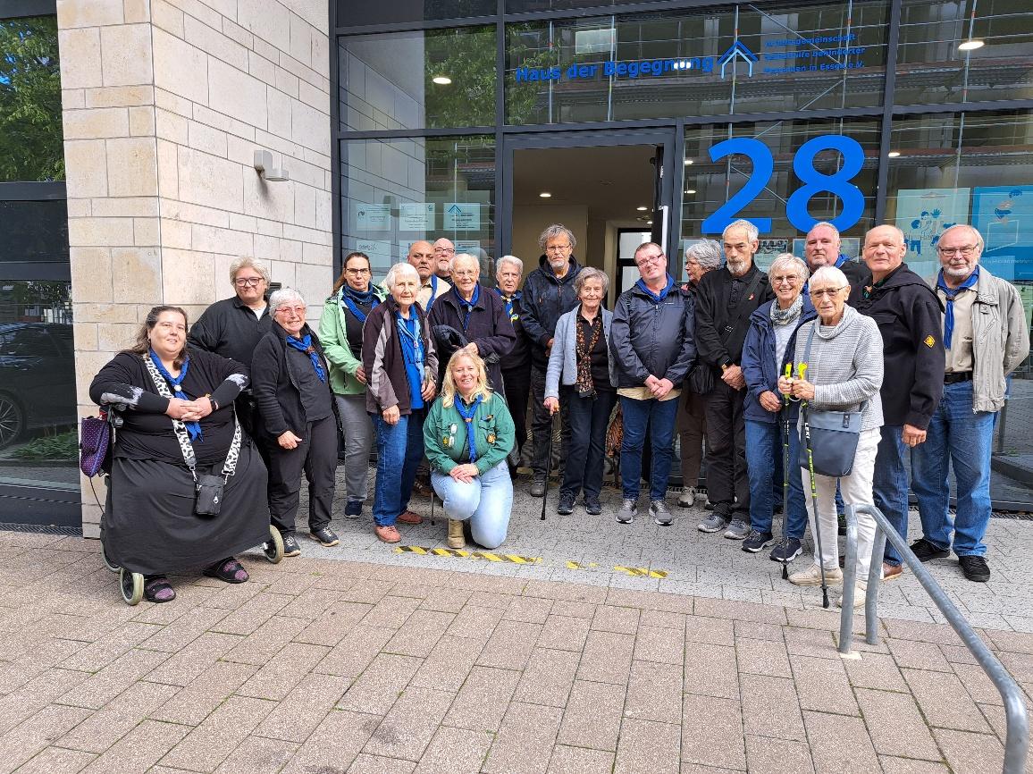 Gruppenbild vom Regionstag NRW 2025 vor dem Haus der Begegnung in Essen: etwa 20 Personen in schwarzen, grünen und beige-farbenen Hemden, eine Person nutzt einen Rollator.