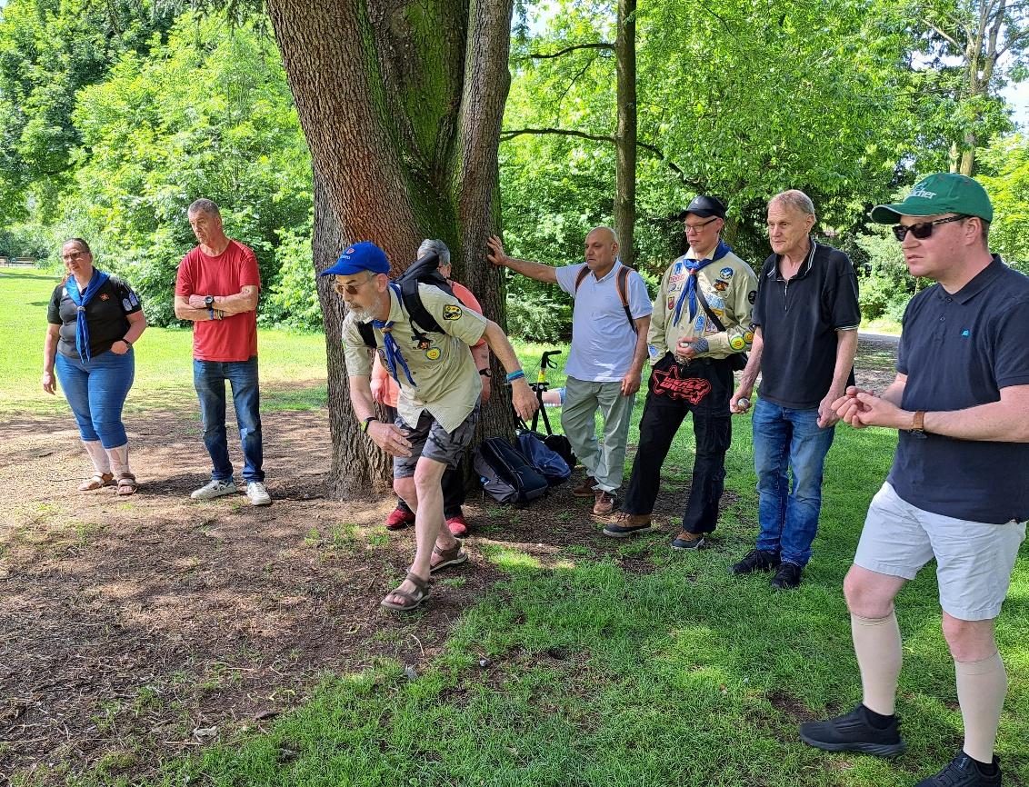 Fahrt 2026 nach Düsseldorf: acht Personen beim Boule-Spiel im Hofgarten, zwei davon in beige-farbener Pfadfinderkluft